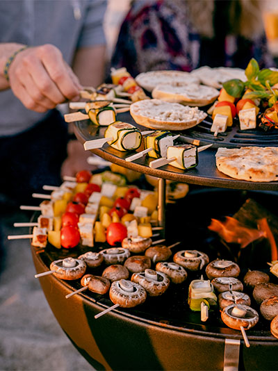 Illustrated is a large grill with food on it, with the BOWL 70 Warming Ring.