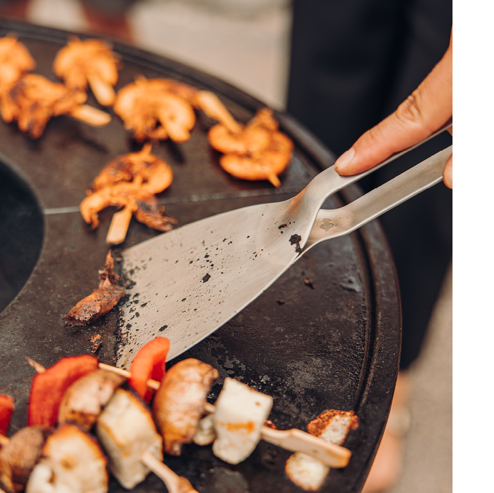 A person is cleaning the Bowl plancha with a scraper