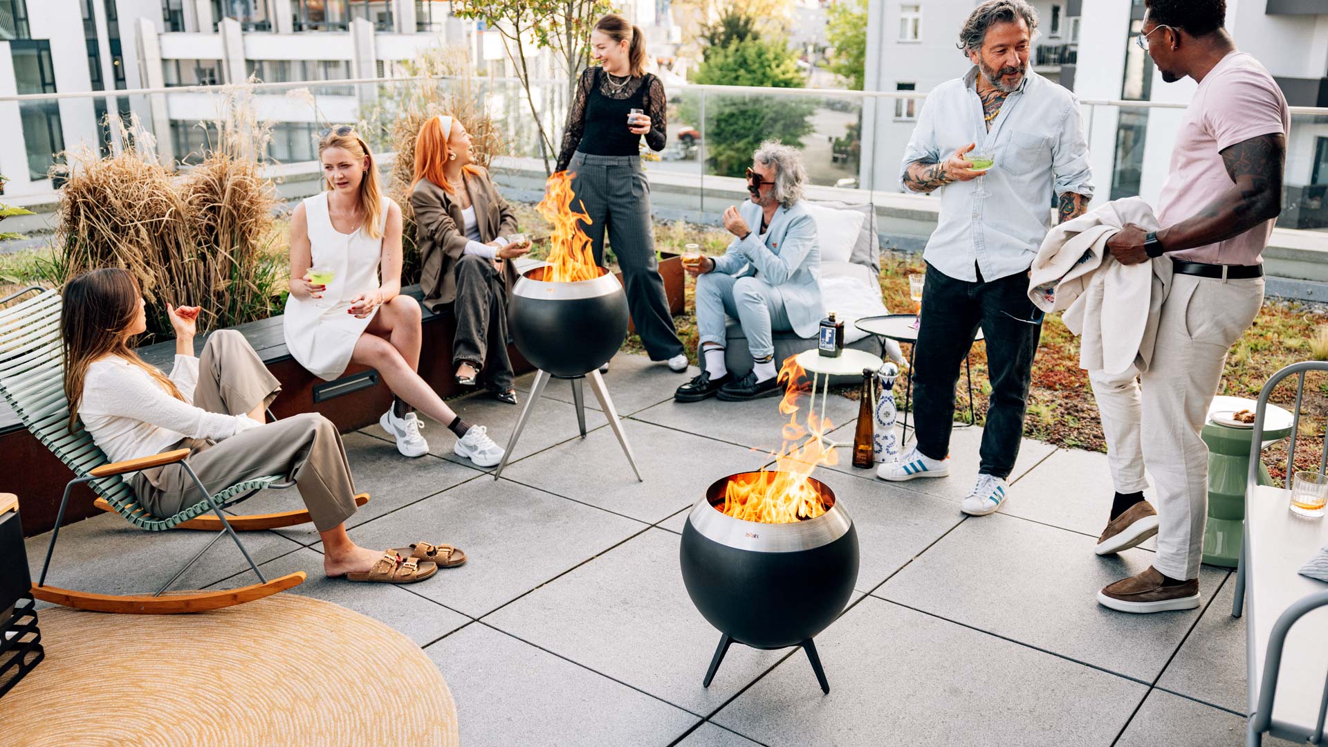 A group of people sitting around a fire pit the 00716 Moon 45 with low stand complements the moment with its thoughtful design.