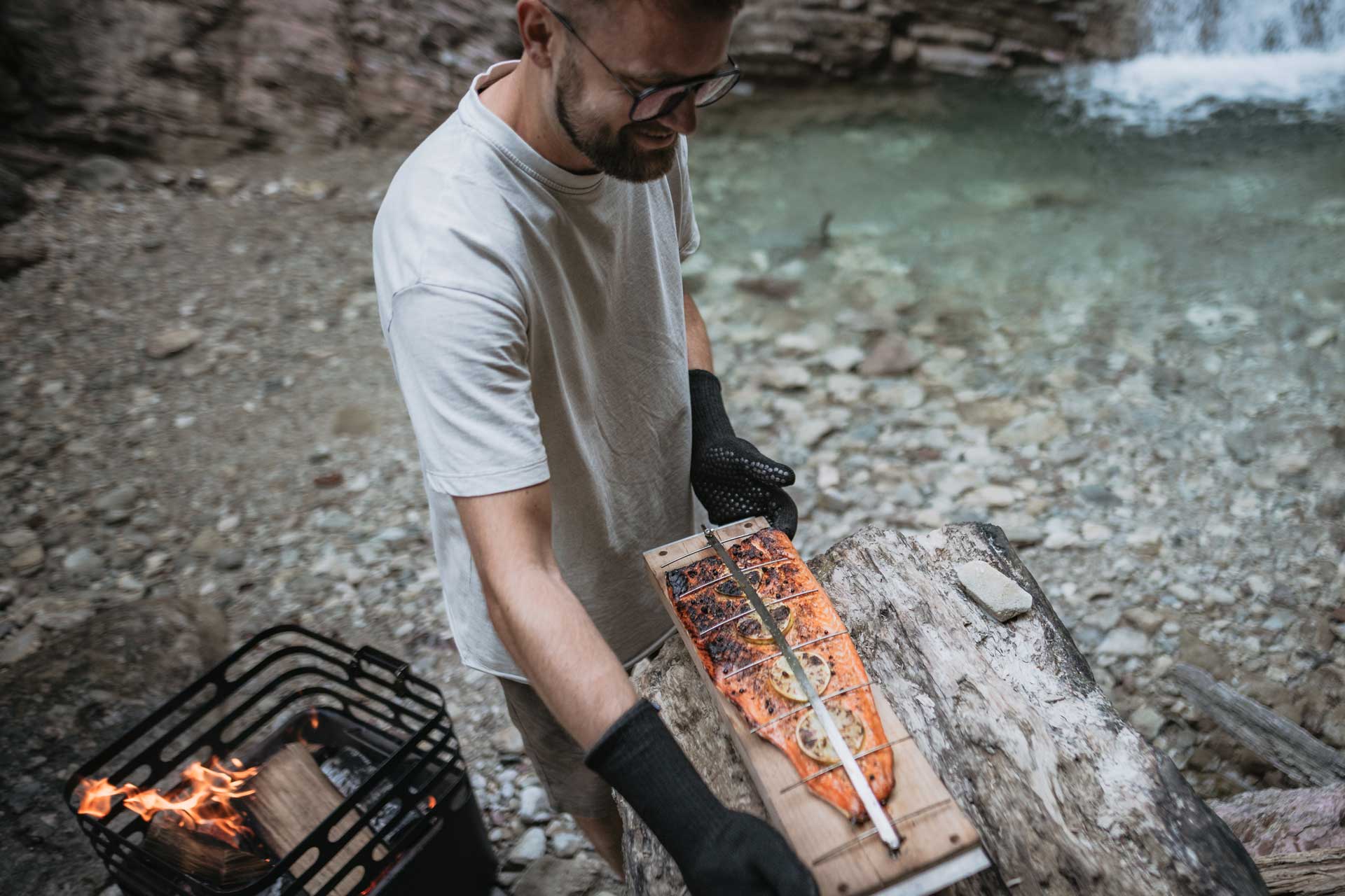 A man is cooking on a campfire, with the Cube Ocean Set adding a functional and elegant touch to the scene.