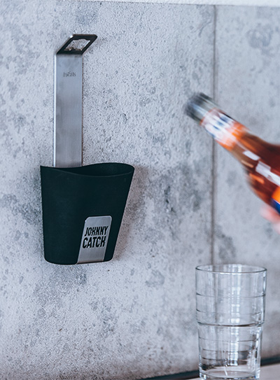 A bottle of alcohol is being poured into a glass, enriched by the presence of the Johnny Catch Cup Bottleopener, which merges design with utility.