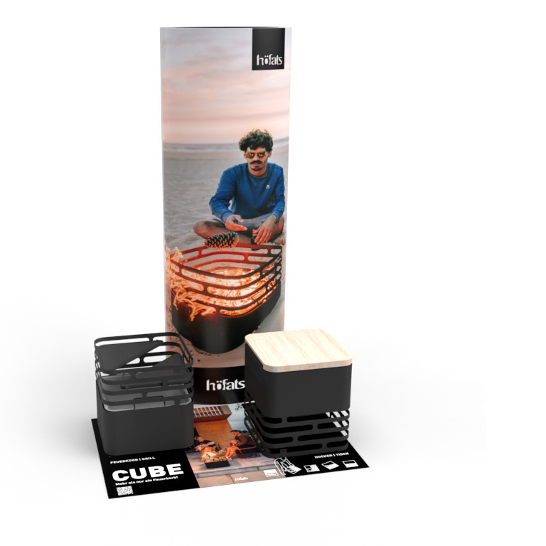 A cardboard column with a man on the beach next to a fire pit on it and a carpet with two Cube Fire Baskets. Showing the Cube POS Set