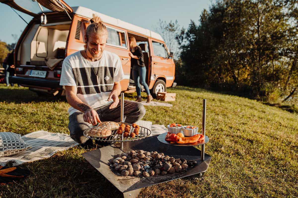TRIPLE Grid 45 Scene showing a man sitting on the grass in front of a camper van, where the Triple Grid 45 stands out for its practical elegance.